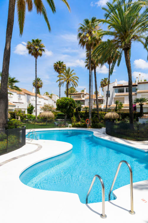 Lujosa piscina en el resort BH Marbella con palmeras, villas blancas y aguas cristalinas bajo cielos soleados
