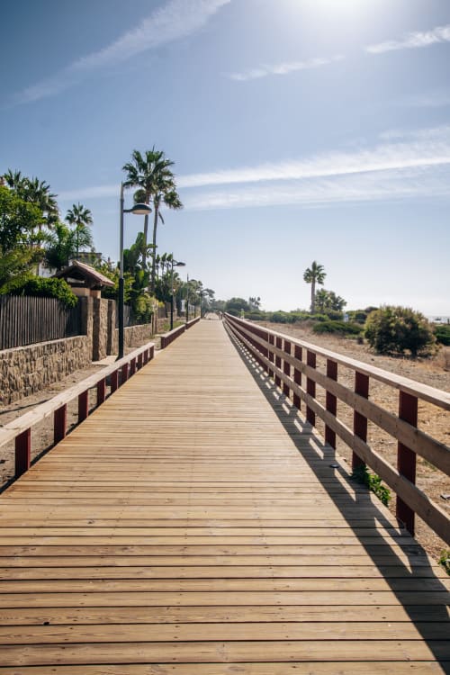 Pasarela de madera con palmeras y vistas al mar en Maui by BH Marbella en Marbella