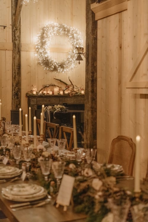 Élégante salle de réception au Domaine du Tertre Ychot décorée d'une couronne illuminée, table aux chandelles et cheminée