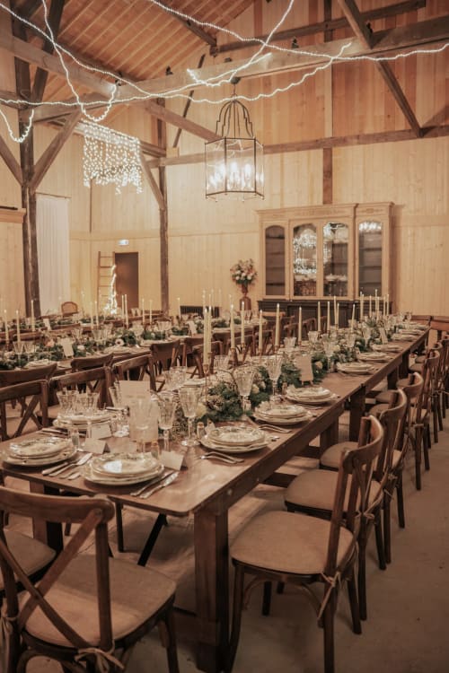 Élégante salle à manger du Domaine du Tertre Ychot avec tables en bois, guirlandes lumineuses et compositions florales à Dol de