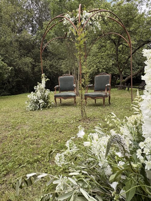 Élégante réception jardins au Domaine du Tertre Ychot avec pergola voûtée, chaises ornementales et fleurs blanches