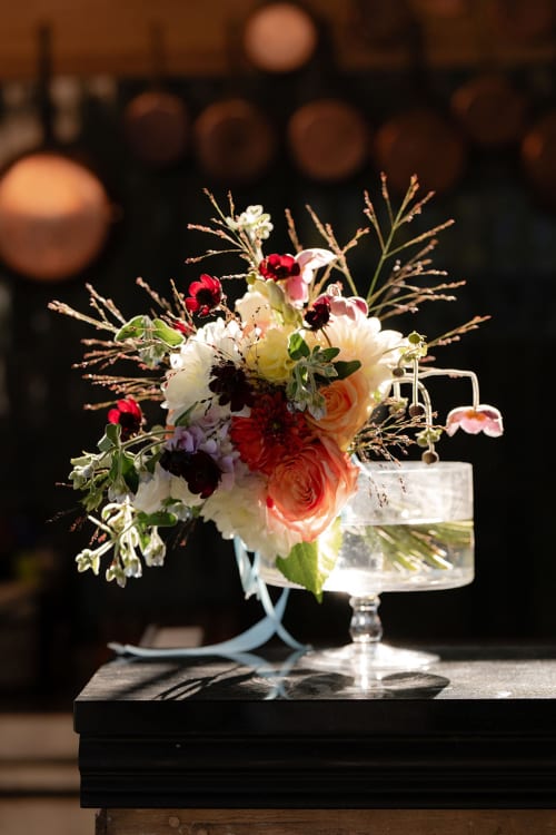 Élégant arrangement floral avec roses rouges et fleurs blanches dans un vase en verre, salle de réception du Domaine du Tertre Ychot, Dol de