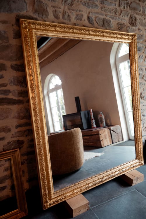 Miroir doré orné reflétant l'élégante chambre du Domaine du Tertre Ychot avec fenêtre, mobilier et téléviseur