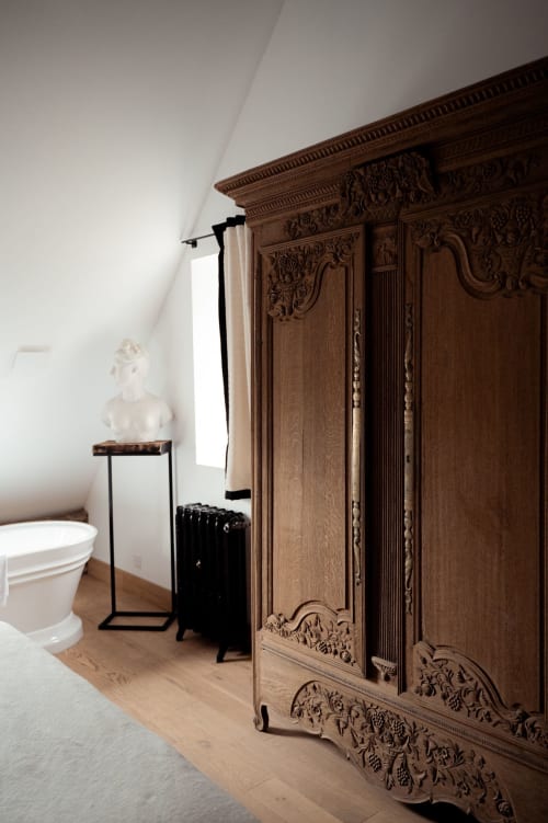 Armoire en bois ornée dans la chambre Les Hirondelles du Domaine du Tertre Ychot à Dol de Bretagne, avec buste blanc et toilettes