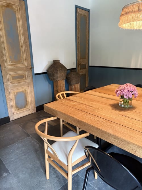 Élégante salle à manger au Domaine du Tertre Ychot avec table en bois, chaises naturelles, fleurs roses et portes-fenêtres classiques