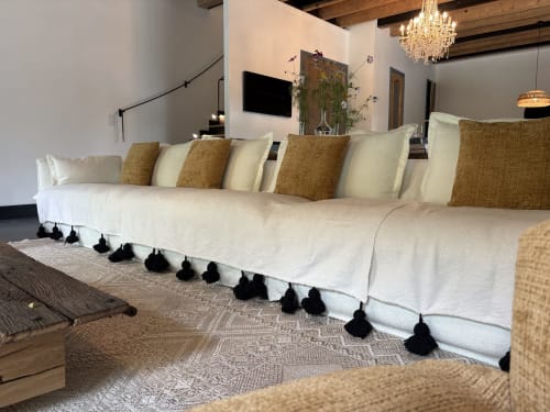 Luxueux canapé sectionnel crème aux coussins dorés et franges noires de la suite Les Hirondelles au Domaine du Tertre