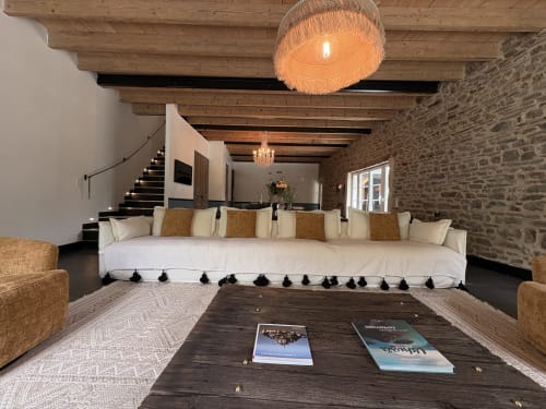 Spacieux séjour du Domaine du Tertre Ychot avec canapé blanc, poutres en bois, murs en pierre et décoration moderne élégante à Dol