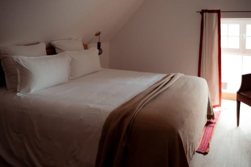Chambre lumineuse aux Hirondelles du Domaine du Tertre Ychot, literie blanche, plaid marron et vue sur le jardin à Dol de