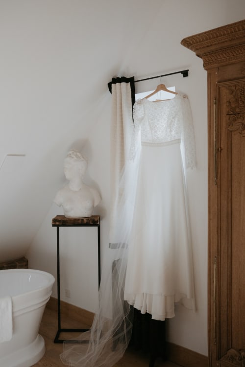 Élégante robe de mariée blanche sur portant noir dans la salle Les Hirondelles du Domaine du Tertre Ychot, Dol de Bretagne