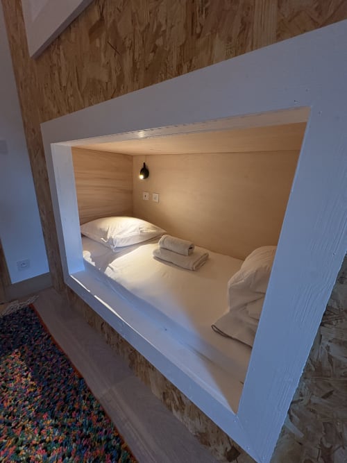 Alcôve lit intégrée au cadre blanc, intérieur bois, oreiller, serviettes pliées, lampe suspendue au Domaine du Tertre Ychot