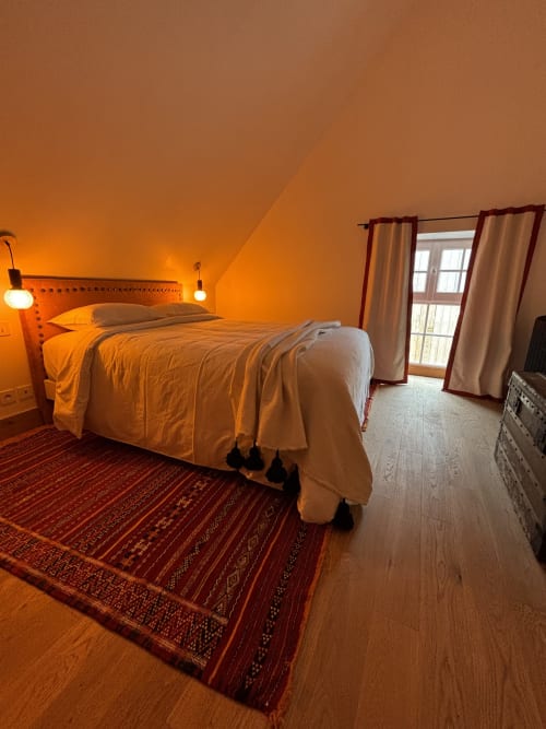 Chambre chaleureuse au Domaine du Tertre Ychot avec lit, tapis rouge à motifs et portes donnant sur le jardin à Dol de Bretagne