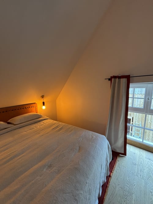 Chambre douillette sous les combles au Domaine du Tertre Ychot, éclairage chaleureux, literie blanche et vue sur le jardin