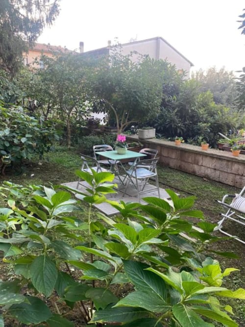 Rigoglioso giardino con tavolo da pranzo, sedie e orto presso Il Giardinetto di Elelú a Orvieto, circondato da edifici moderni