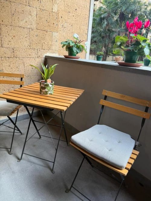 Area salotto della terrazza di Il Giardinetto di Elelú a Orvieto con tavolo in legno, sedie, cuscini e vasi di fiori