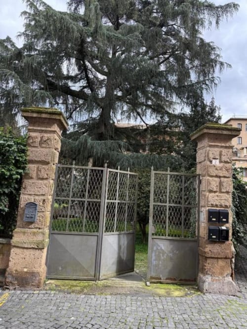 Antico ingresso in pietra con porte in metallo e salice piangente all'Il Giardinetto di Elelú B&B di Orvieto