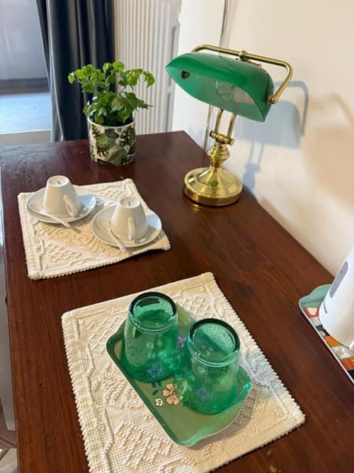 Elegante scrivania doppia con lampada da tavolo verde stile banca, pianta in vaso, tazza e piattino bianchi e bicchieri verdi presso Il Giardinetto