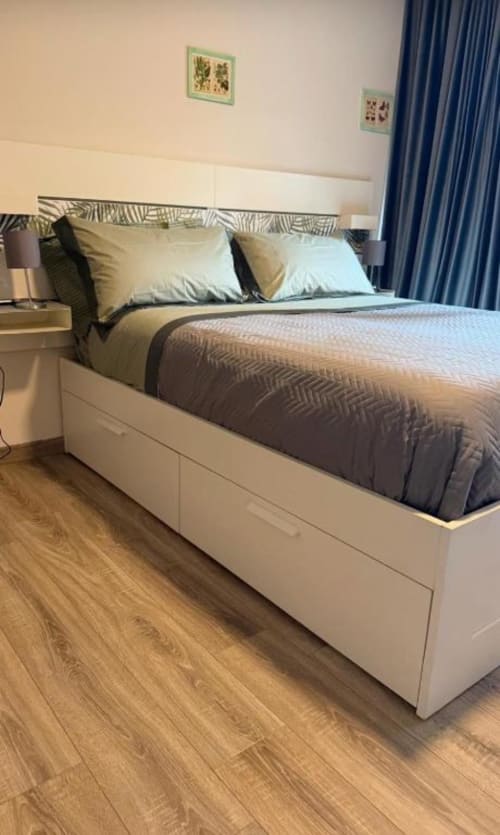 Camera da letto matrimoniale moderna presso Il Giardinetto di Elelú a Orvieto con letto a struttura bianca, biancheria beige, tende blu e arredamento in legno