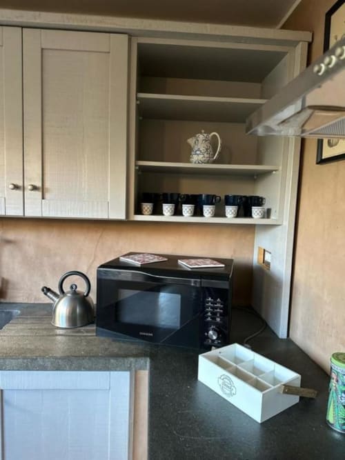 Angolo cucina della struttura B&B di Orvieto con microonde, bollitore, piano di lavoro nero e mensole aperte con elementi decorativi