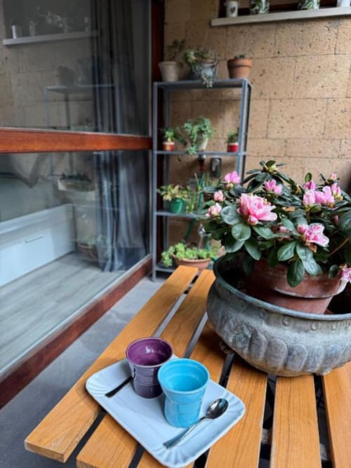 Seduta in terrazza presso Il Giardinetto di Elelú B&B a Orvieto con fiori rosa e caffè del mattino