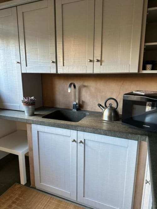 Cucina moderna con mobili bianchi, piano di lavoro scuro, lavello, bollitore e fornello nell'appartamento di Orvieto