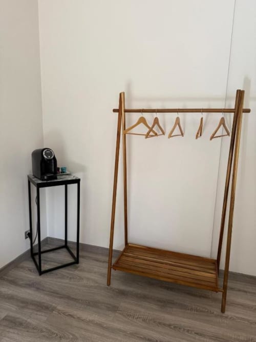 Appendiabiti in legno con grucce nella camera Il Giardinetto di Elelú, B&B di Orvieto, accanto a un tavolino nero con caffettiera