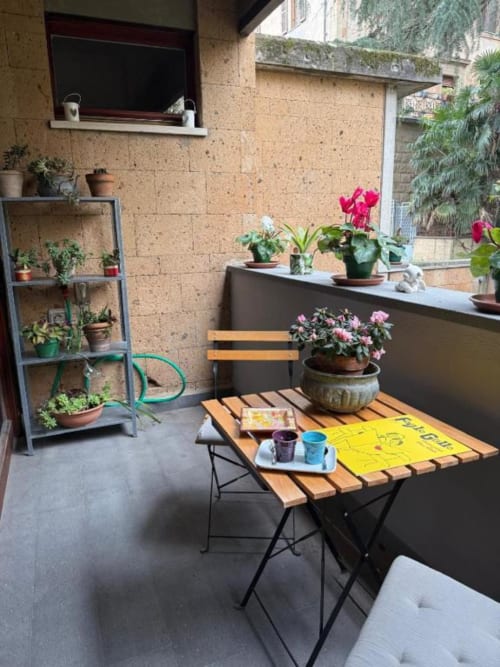 Affascinante terrazza di Il Giardinetto di Elelú a Orvieto con fiori in vaso, tavolo in legno e muro in mattoni