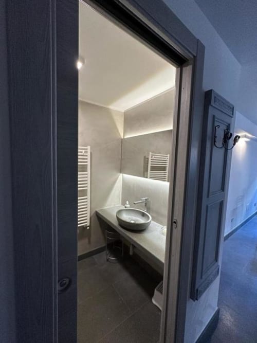 Bagno moderno nella B&B di Orvieto con lavabo circolare, specchio illuminato, scaldasalviette e finiture in piastrelle neutre