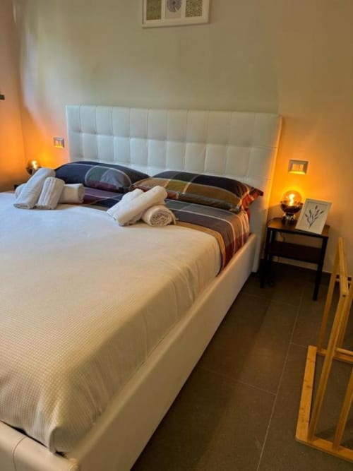 Camera moderna in Il Giardinetto di Elelú B&B, Orvieto, con letto bianco imbottito, illuminazione calda e pavimento in piastrelle scure.