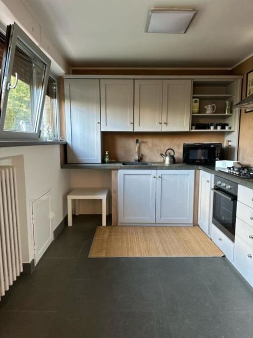 Cucina moderna con armadi bianchi, piani di lavoro scuri e pavimento in legno presso Il Giardinetto di Elelú B&B a Orvieto