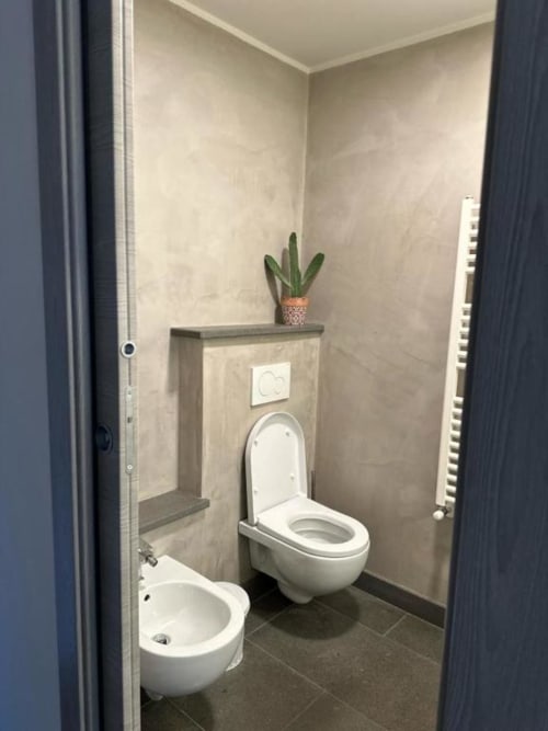 Bagno moderno nel B&B di Orvieto con bidet e WC, piastrelle beige, cactus in vaso e scaldasalviette.