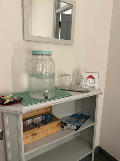 Angolo cottura del B&B di Orvieto con dispenser in vetro per bevande, tazze e decorazioni su scaffalature bianche