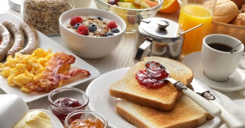Full breakfast spread at Kmetija Pečnik B&B featuring toast with jam, eggs, bacon, cereals, fresh fruit, coffee and juice.