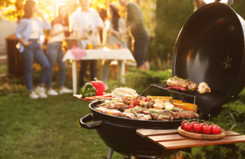 Backyard BBQ gathering at Clos Céleste with grilled meats, vegetables, and guests enjoying golden hour in Normandy
