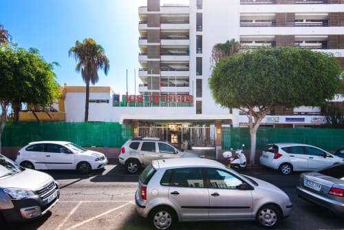 Fachada del apartamento Home Stay Gran Canaria en San Bartolomé de Tirajana con coches aparcados y palmeras