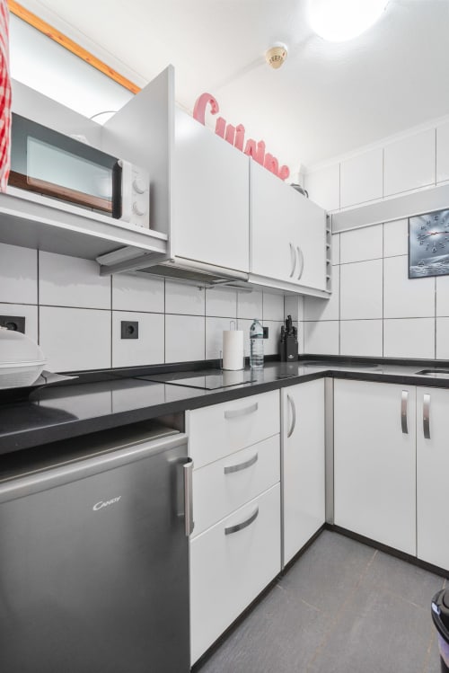 Cocina moderna blanca con encimeras negras, electrodomésticos de acero inoxidable y salpicadero de azulejos en apartamento de Gran Canaria