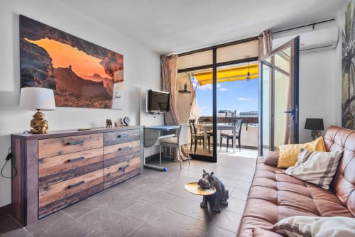 Apartamento moderno con balcón vista al mar, cómoda de madera, sofá rosa y obra costera en San Bartolomé de Tirajana