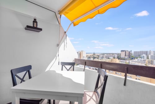 Soleada terraza en azotea con toldo amarillo, mesa de comedor y vistas a la ciudad en Gran Canaria