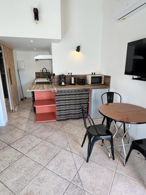 La kitchenette du cottage Terracota avec coin repas, cuisinière, micro-ondes et TV au Romulus, Roumoules