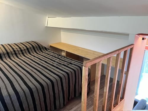 Chambre cosy mansardée du gîte Le Romulus à Roumoules avec literie rayée et mobilier en bois
