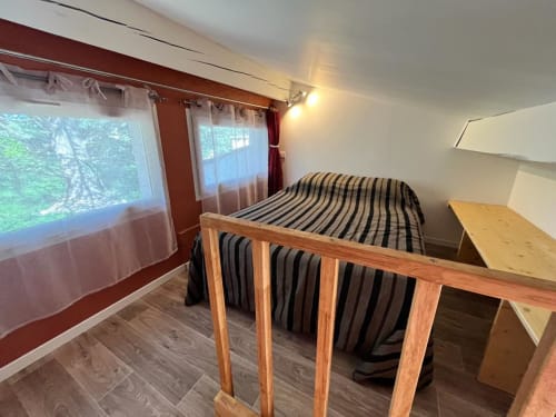 Chambre confortable du gîte Le Romulus avec lit rayé, cadre en bois, vue sur le jardin et bureau de travail à Roumoules