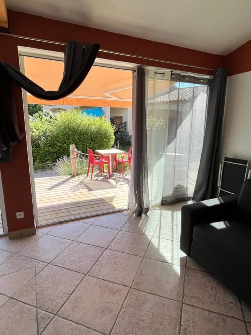 Le cottage Romulus avec sa chambre en terre cuite ouvrant sur la terrasse de jardin aux chaises rouges et haies vertes, Roumoules
