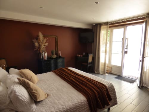 Spacious double bedroom at Les Rives De La Tronne with burgundy accent wall, large bed, and glass doors opening to terrace in