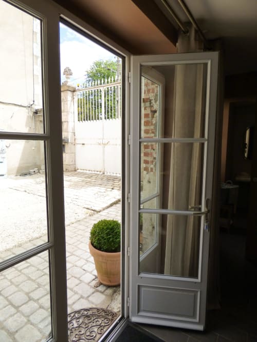 Open glass doors leading to patio with potted plant, Les Rives De La Tronne, Mer, France