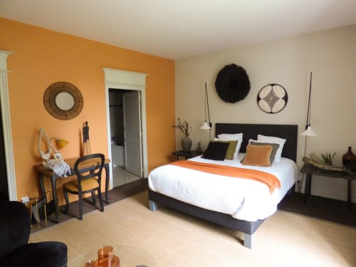 La Chambre Safran aux Rives de la Trône propose un lit noir avec un chemin de table orange, un mur d'accent orange et une décoration moderne.