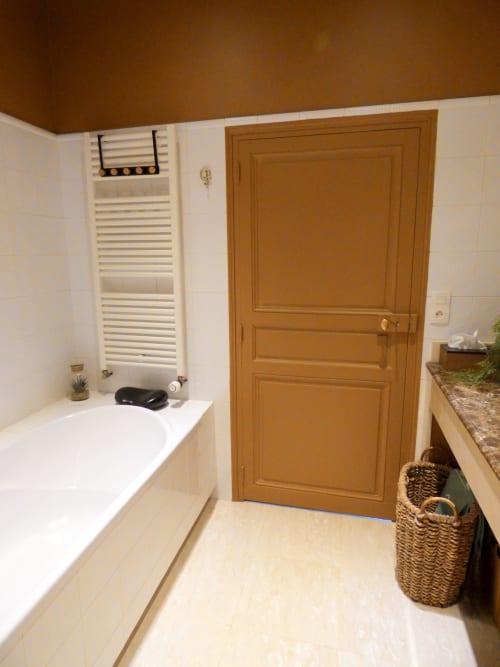 Modern bathroom with white tub, towel rack, wooden door and stone countertop at Les Rives De La Tronne hotel