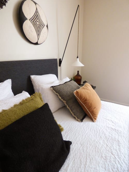Contemporary bedroom at Les Rives De La Tronne featuring dark headboard, white bedding, colorful pillows, and modern pendant