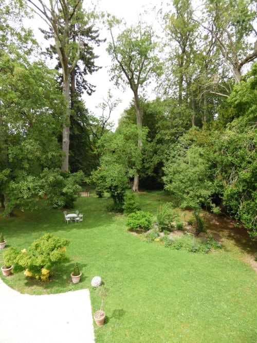 Lush garden grounds at Les Rives De La Tronne in Mer, France with manicured lawn, mature trees, and outdoor seating area