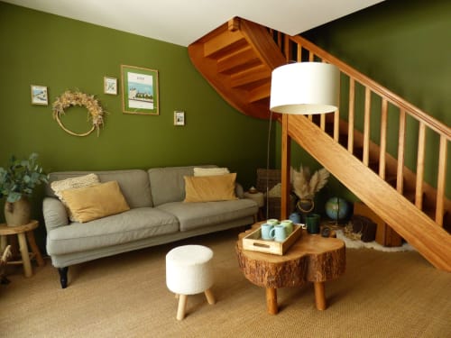 Cozy duplex living room at Les Rives De La Tronne with green walls, gray sofa, wooden staircase, and rustic décor
