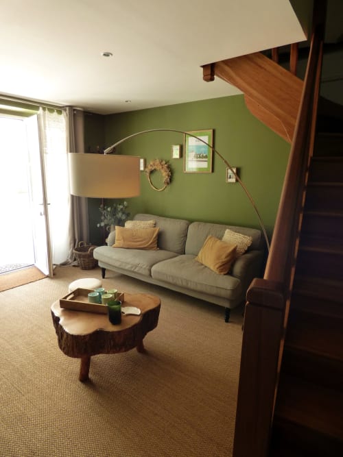 Modern duplex living room at Les Rives De La Tronne with green walls, beige sofa, wooden table, and wooden staircase