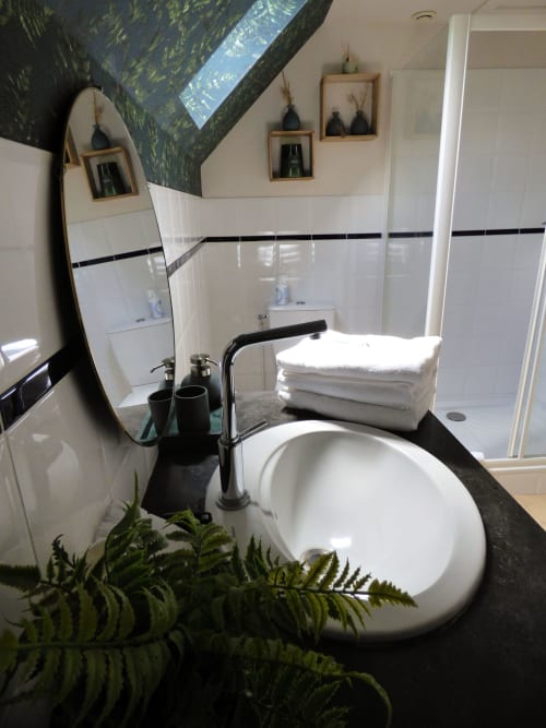 Modern bathroom in La Suite de l'Orangerie duplex at Les Rives De La Tronne, featuring white circular sink, black accents,